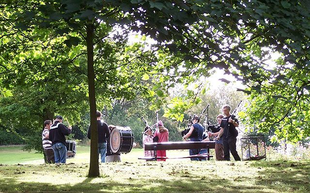 A group of people are standing around a picnic table in a park.