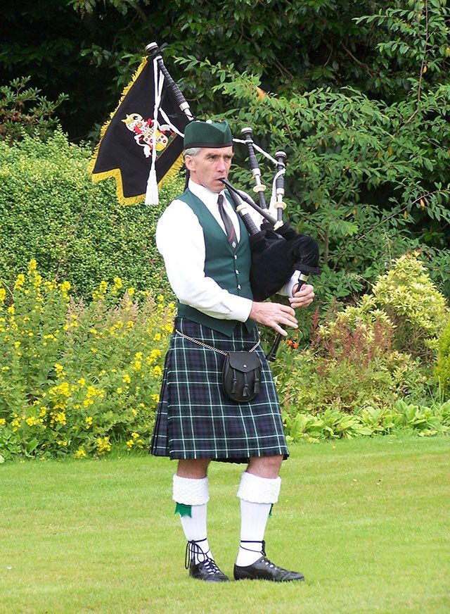 A man in a kilt is playing bagpipes in a field