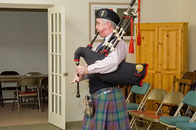 A man in a kilt is playing a bagpipe in a room