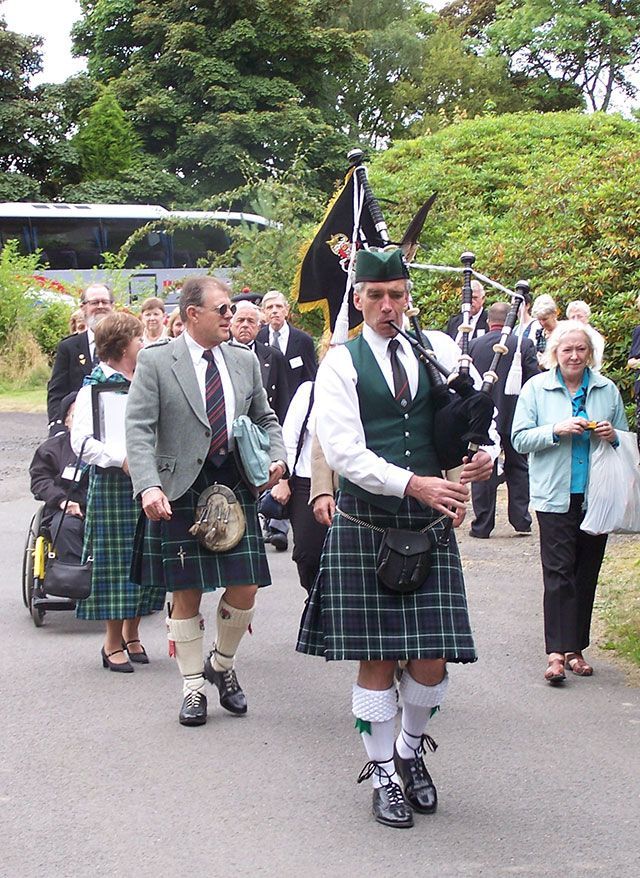 A man in a kilt is playing bagpipes in a parade