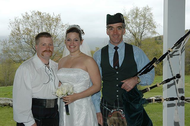 A bride and groom are posing for a picture with a bagpipe player.