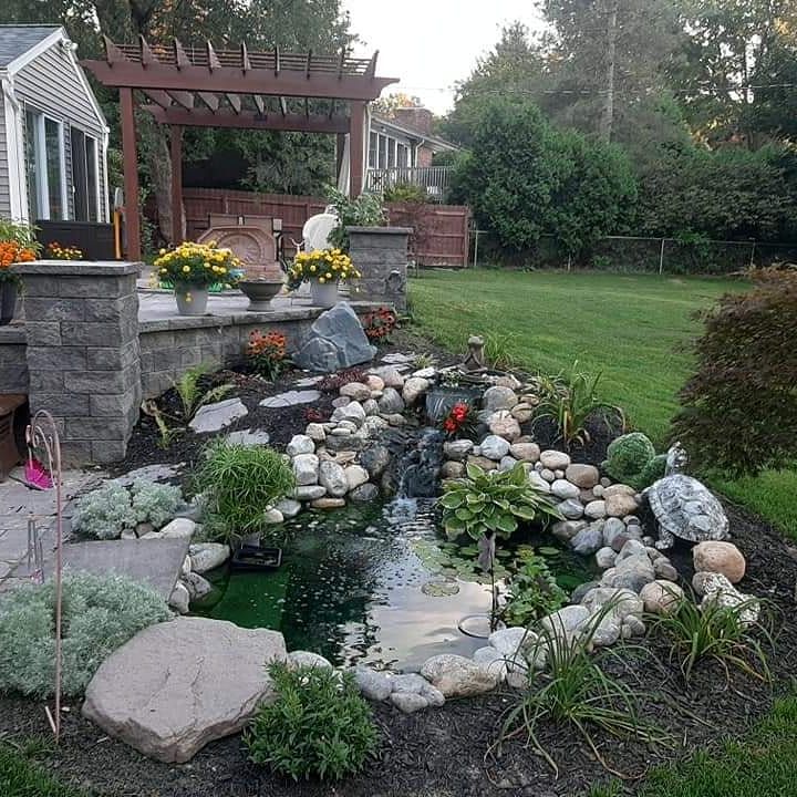 A backyard with a pond surrounded by rocks and flowers