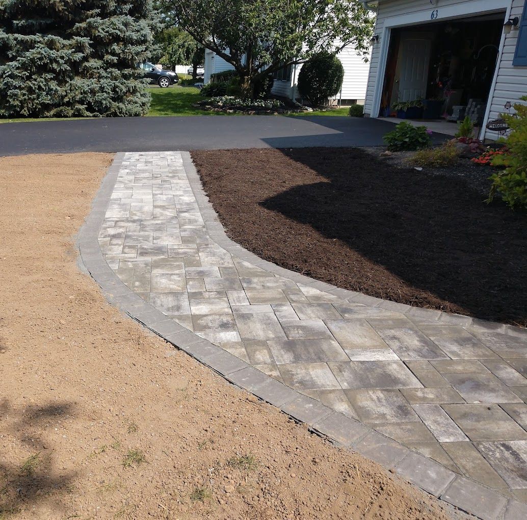 A brick walkway leading to a garage and a house