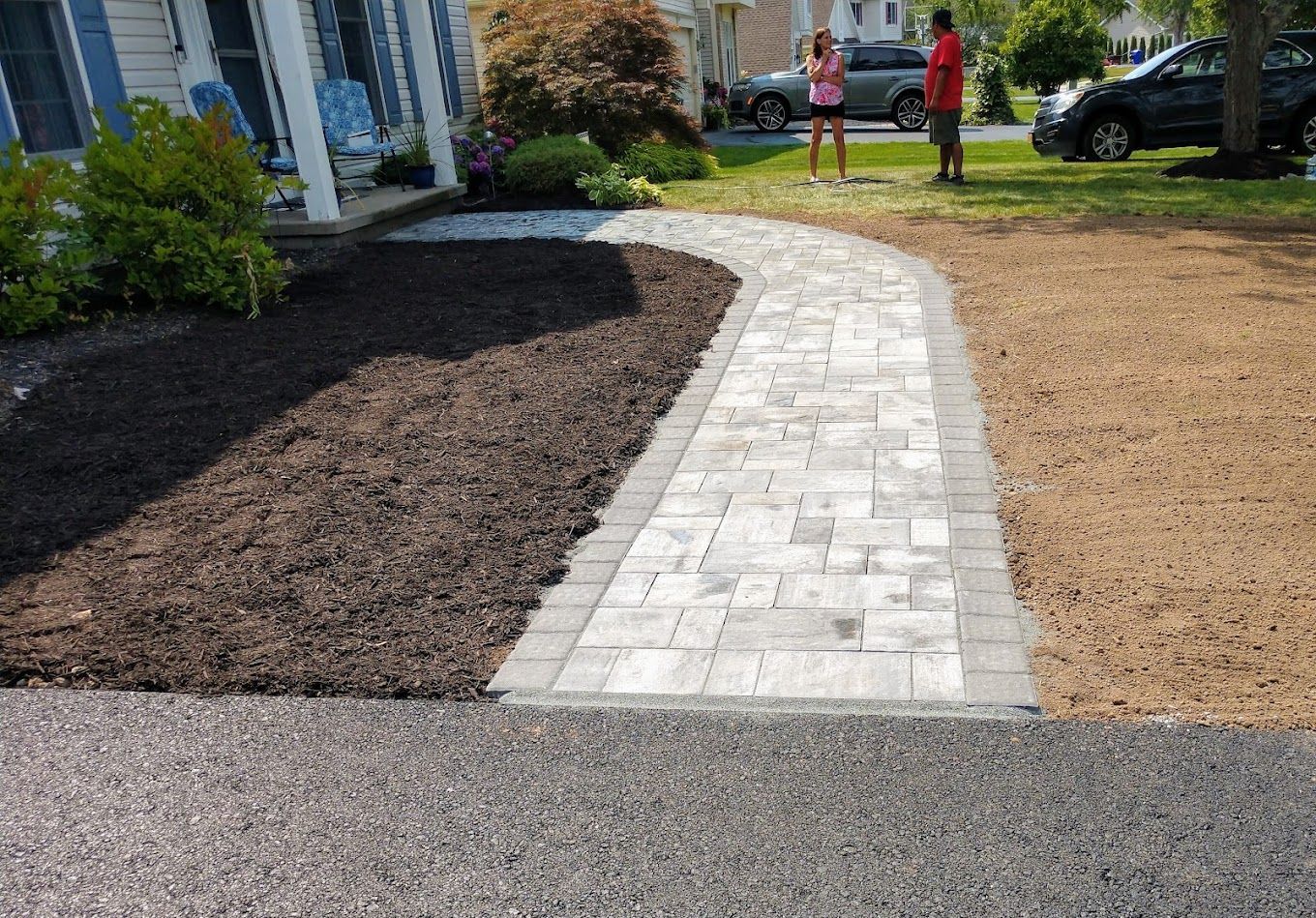 A couple standing on a sidewalk in front of a house.