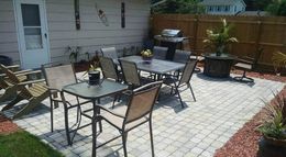 A patio with a table and chairs and a grill.