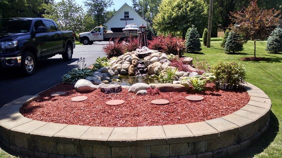 A black truck is parked in a driveway next to a garden with a fountain.