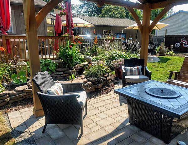 A patio with chairs and a fire pit under a gazebo.