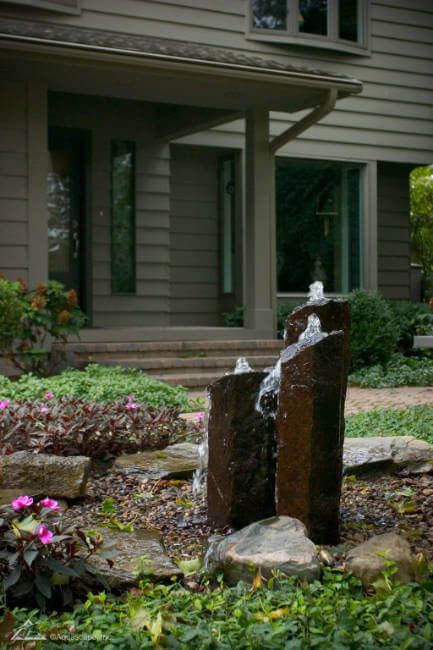A water fountain in front of a house in a garden.