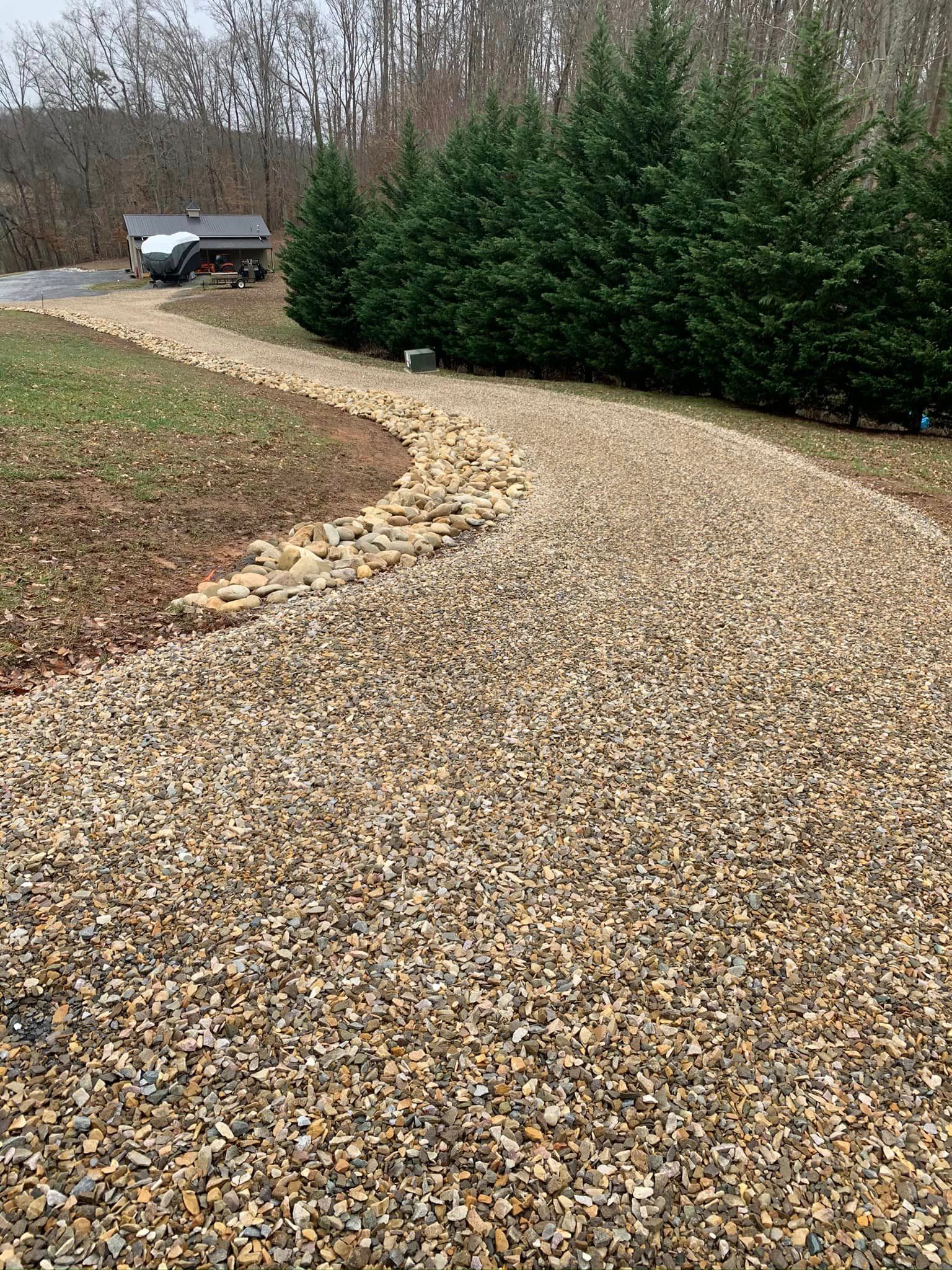A gravel driveway leading to a house in the woods.