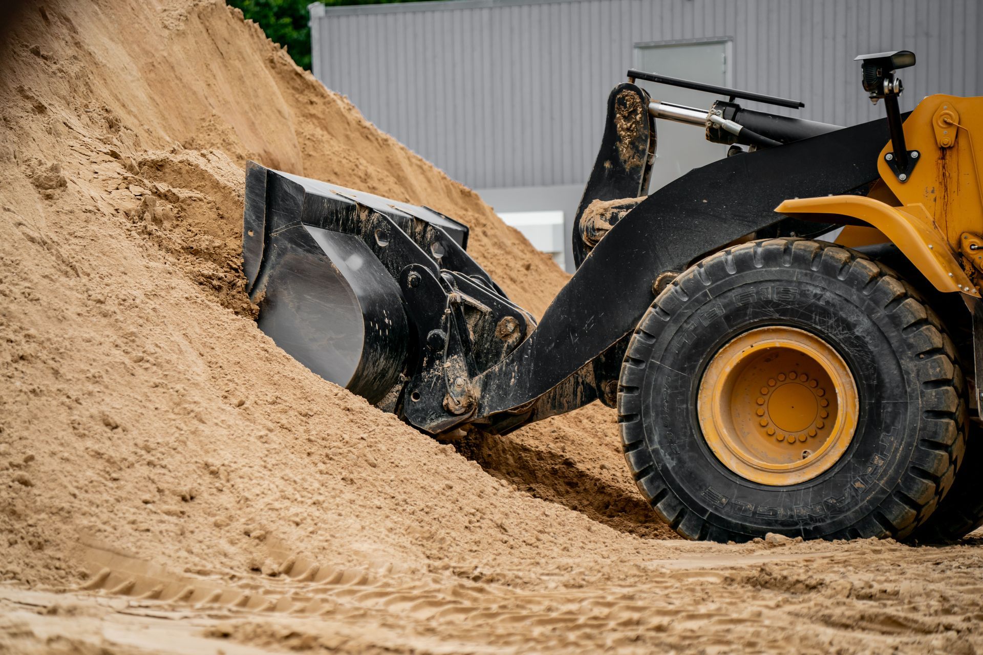 A wheel loader pushing construction sand on a building site. A wheel loader pushing construction sand on a building site.