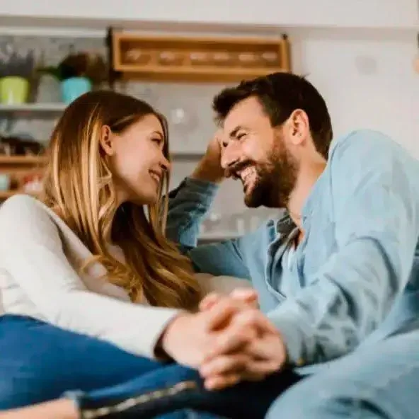 A man and a woman are sitting on a couch looking at each other.