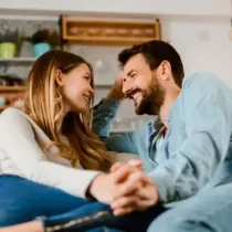 A man and a woman are sitting on a couch looking at each other.