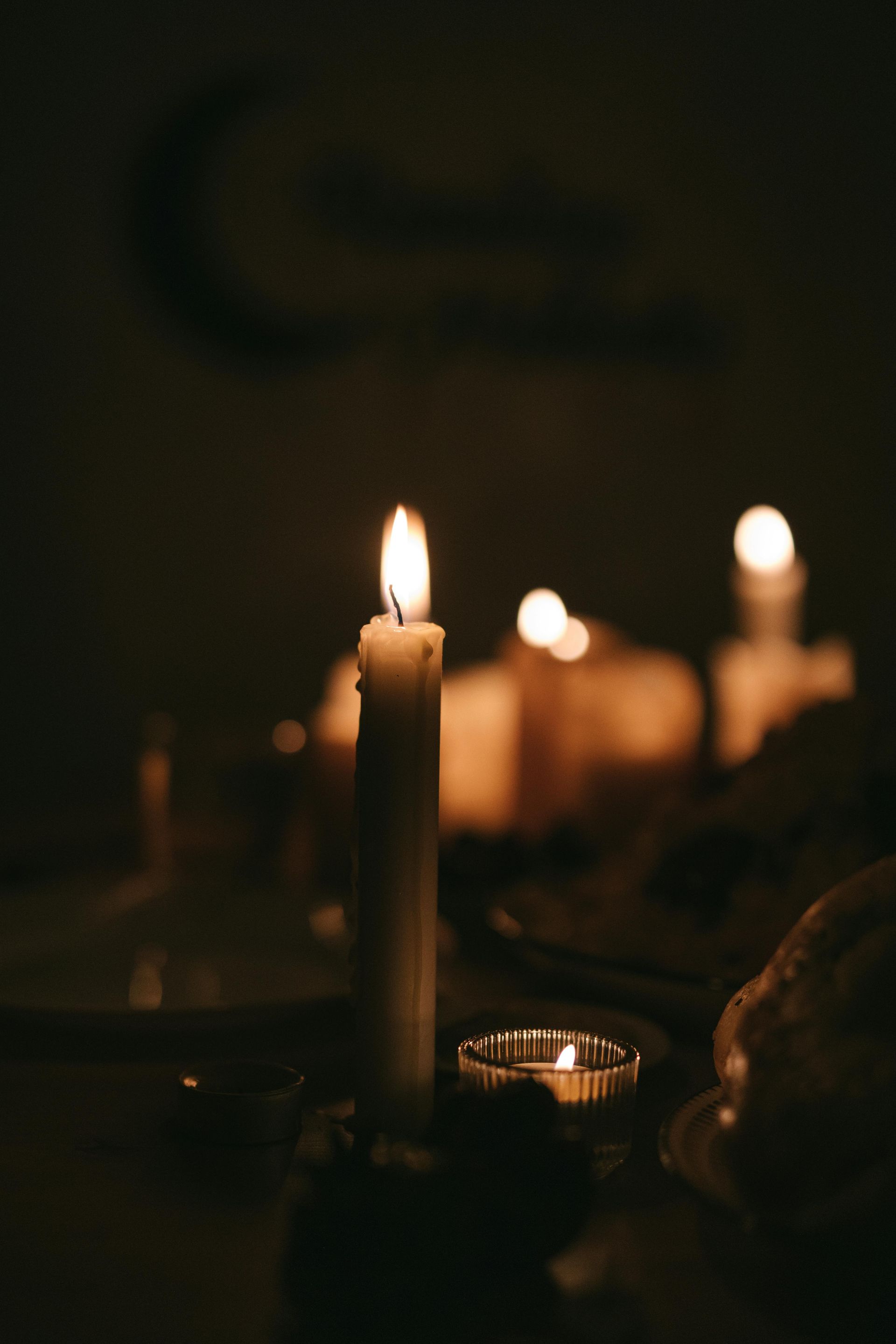A lit candle in a glass on a wooden table.