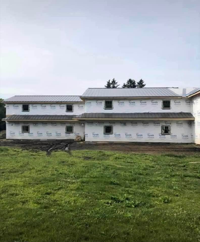 A large white house is being built in a grassy field.