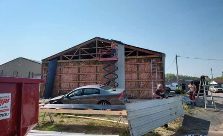 A car is parked in front of a building under construction.