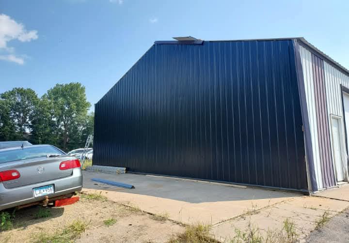 A car is parked in front of a large black building.