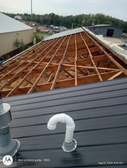 The roof of a building is being built and there is a pipe on the roof.