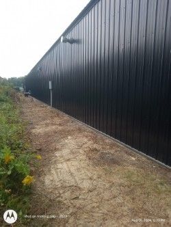A large black building with a dirt path leading to it.
