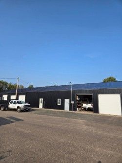 A black building with two white trucks parked in front of it.