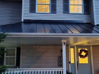 A house with a black roof and a porch with a wreath on it.