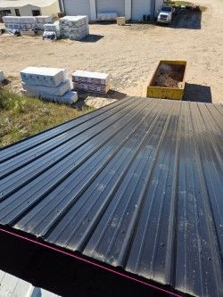 A black metal roof is sitting on top of a dirt field.
