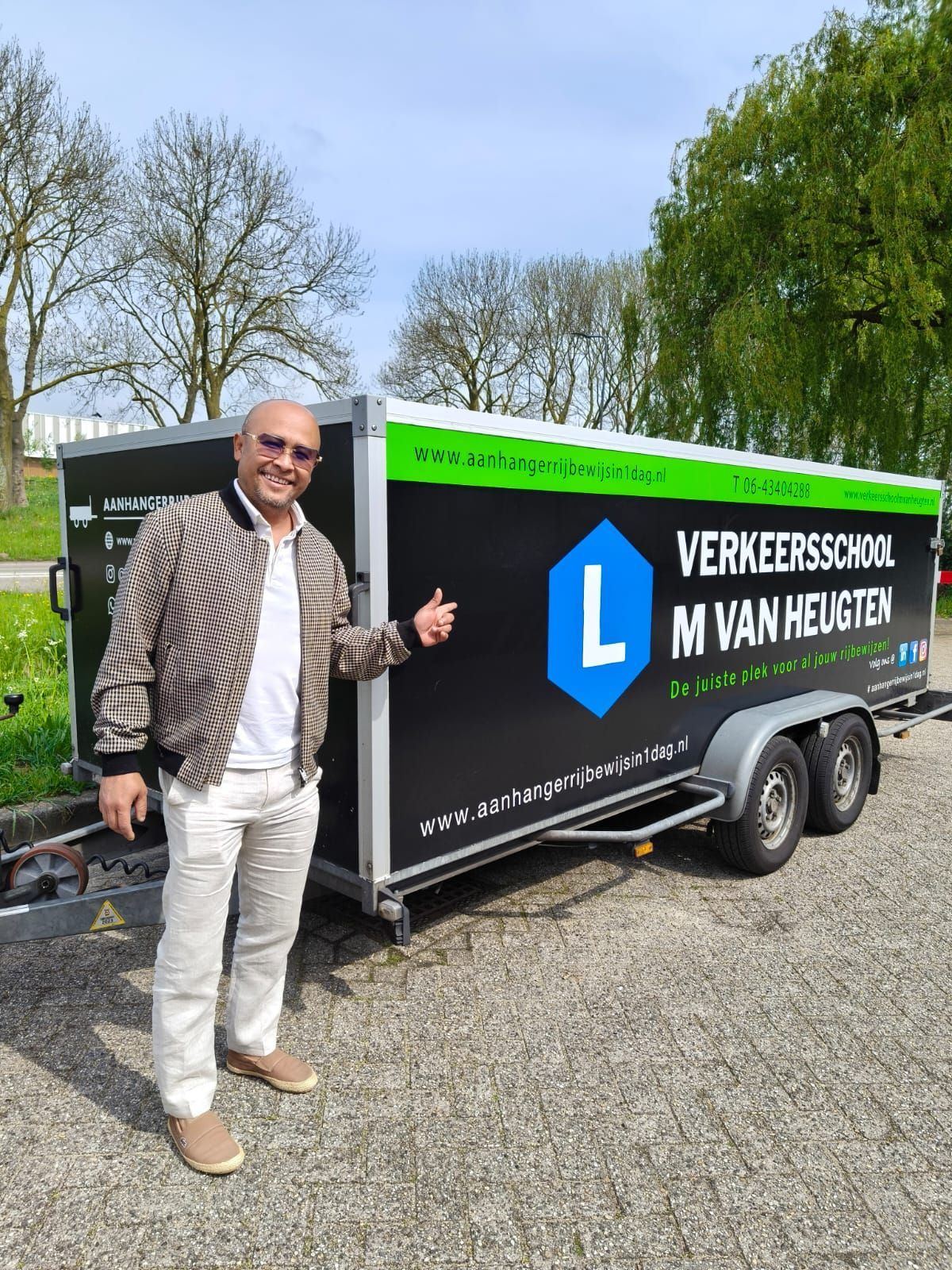 Een man steekt zijn duim omhoog naast een aanhanger met de tekst 