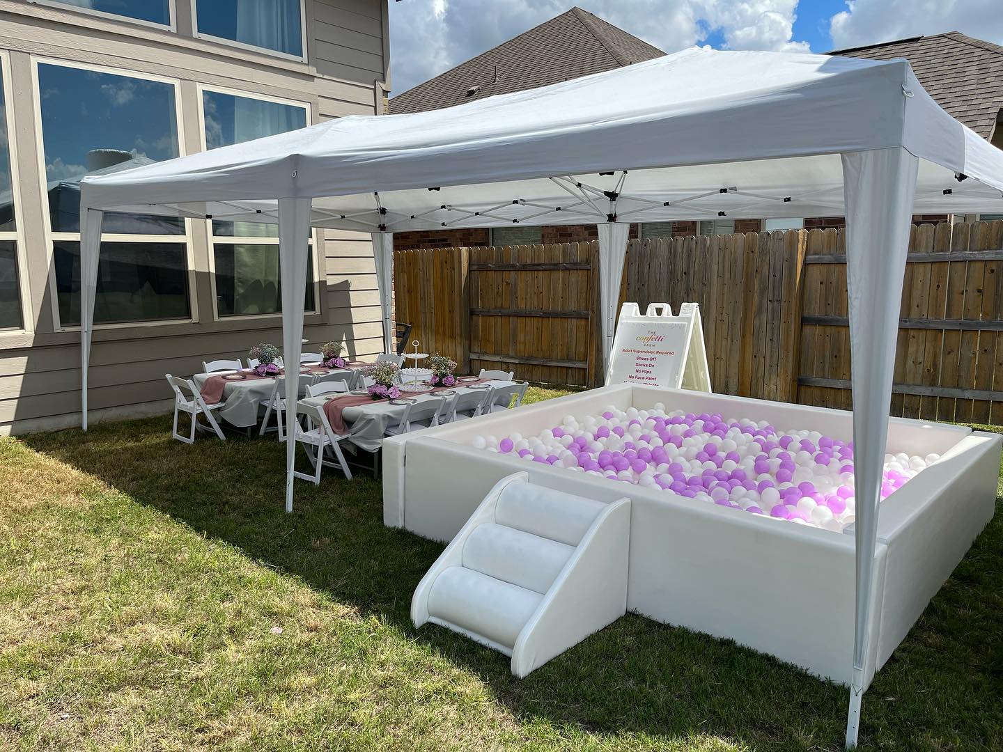 There is a ball pit in the backyard under a tent.