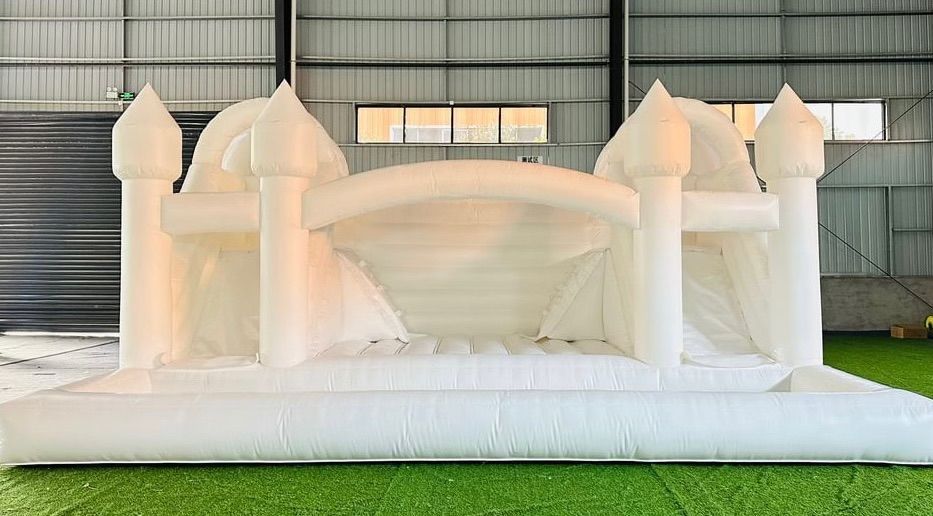 A white bouncy castle is sitting on top of a lush green field.