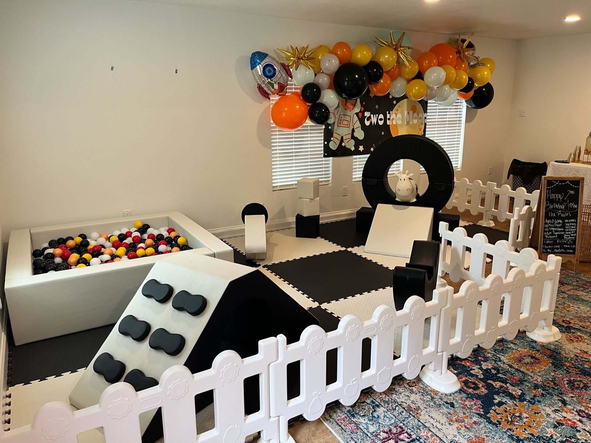 A room with a ball pit and balloons on the wall.