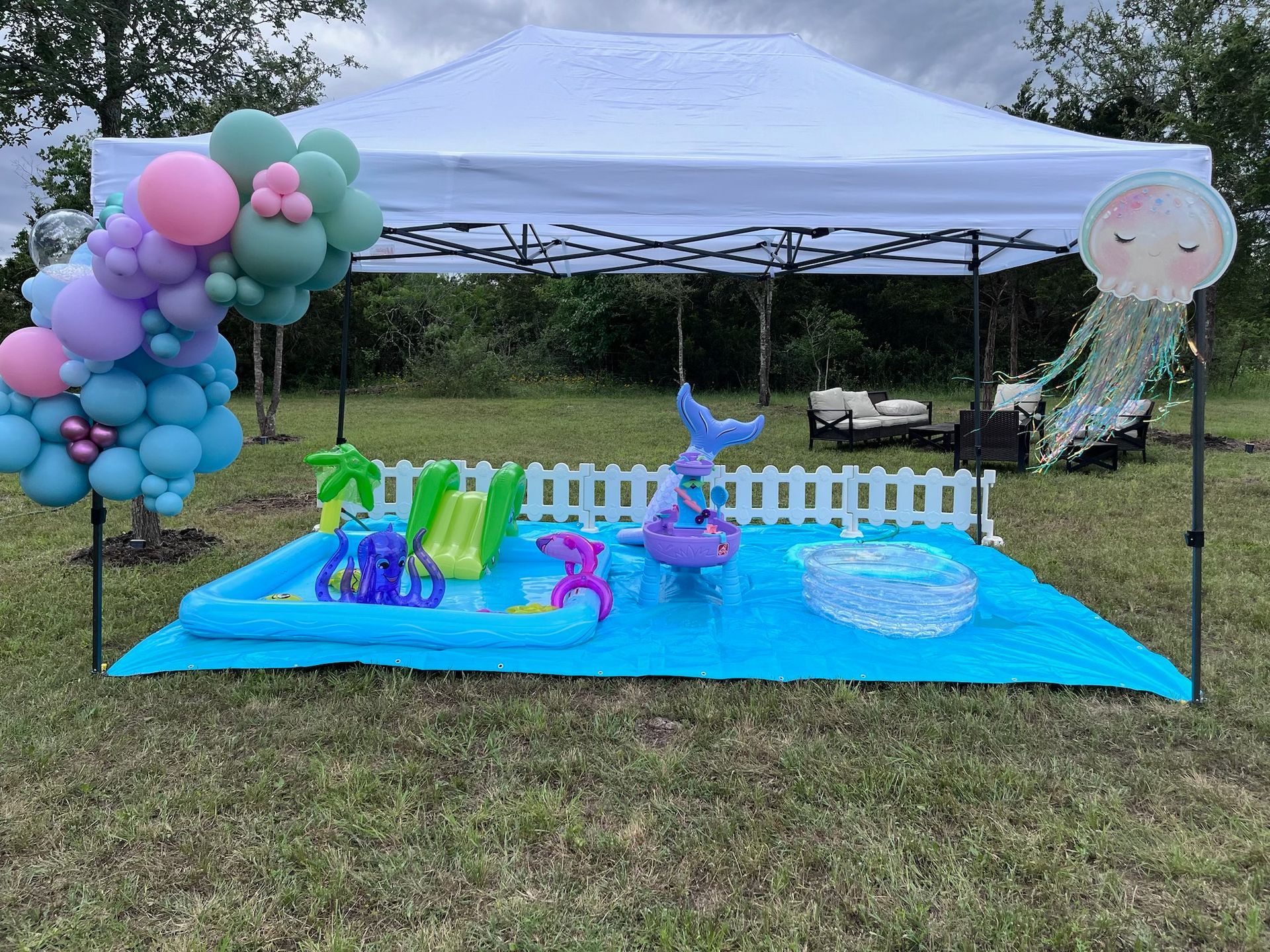 There is a tent with balloons and a pool underneath it.