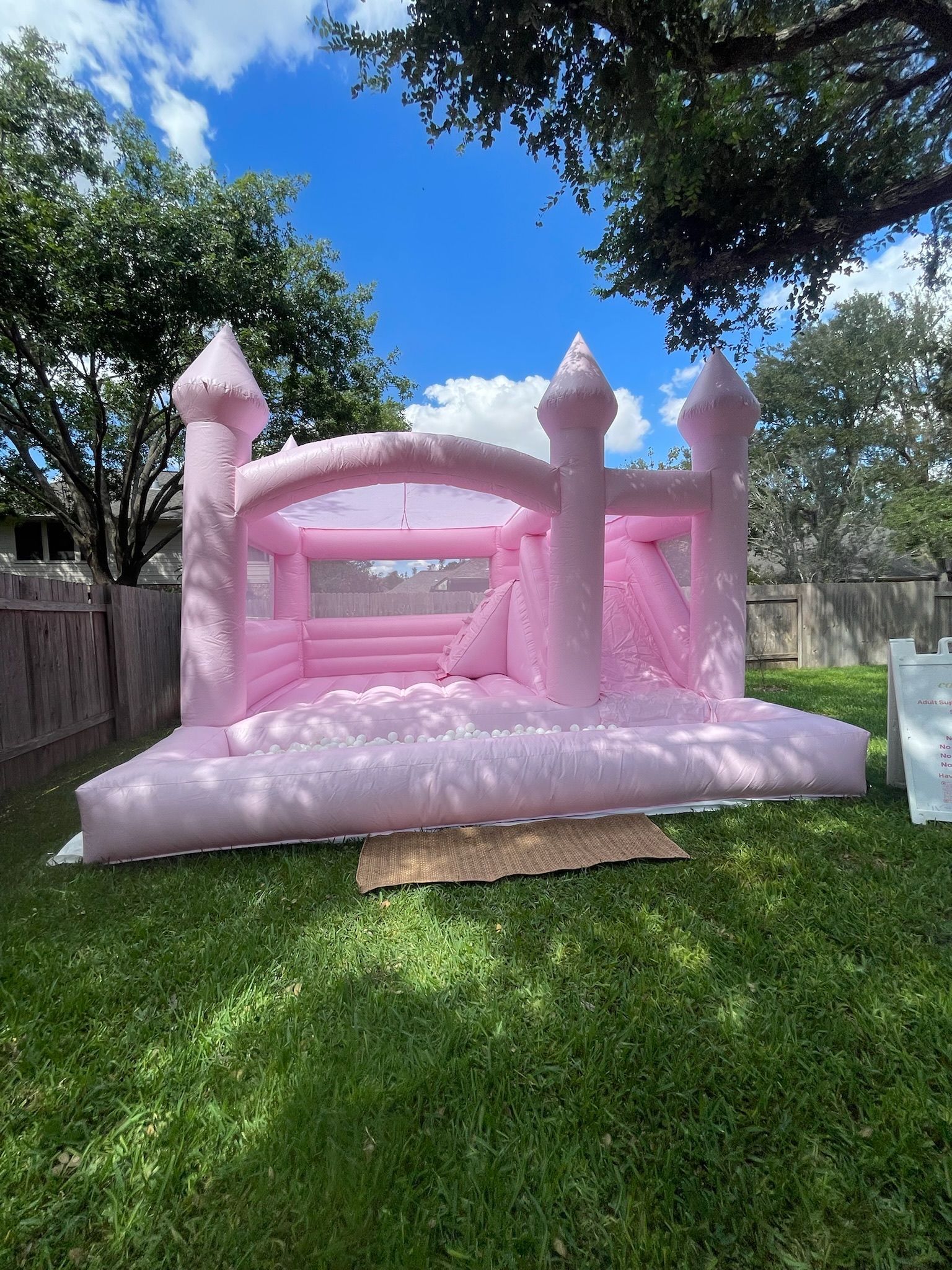 A pink bouncy castle is sitting on top of a lush green lawn.