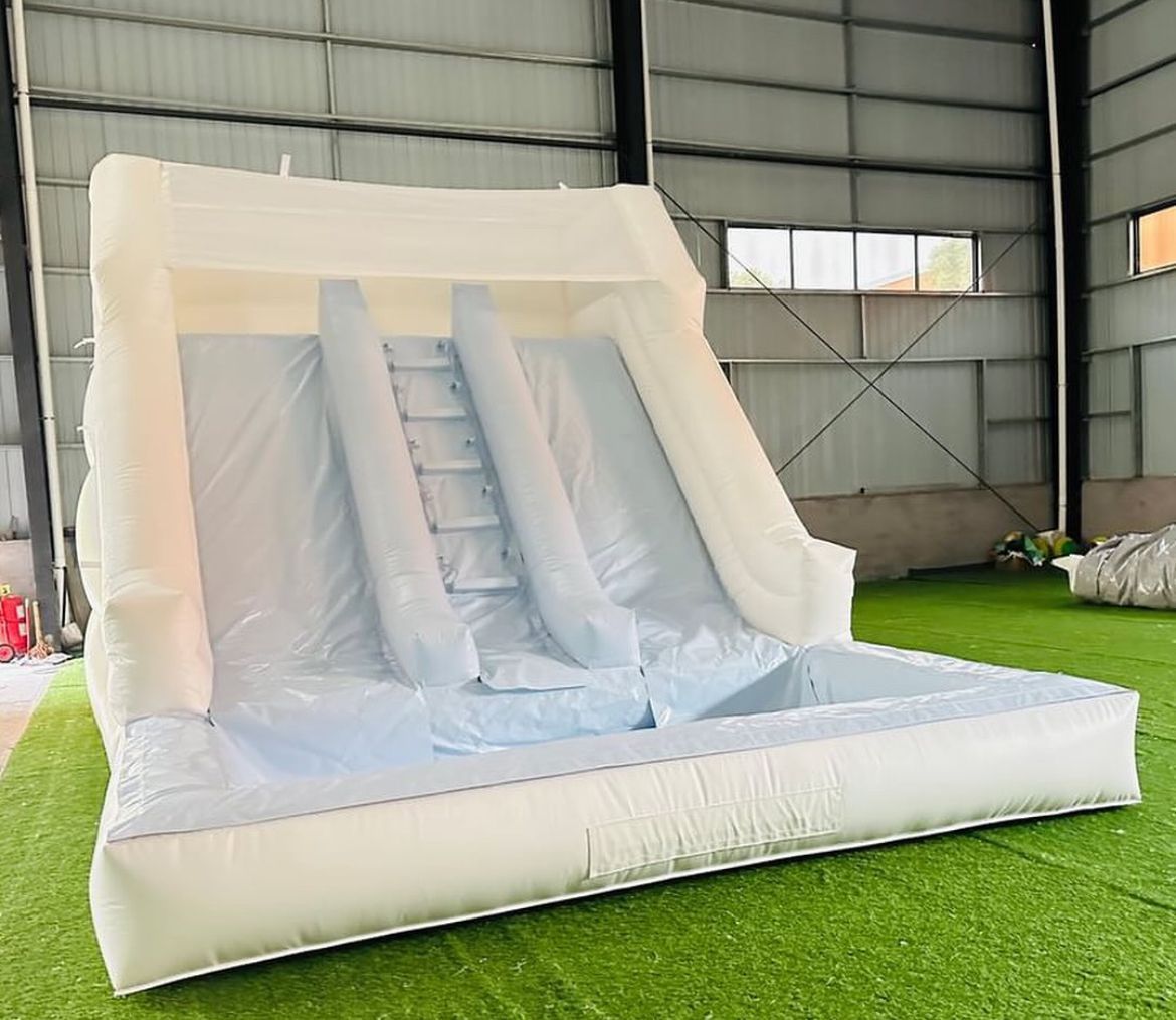 A white inflatable slide is sitting on top of a lush green field.