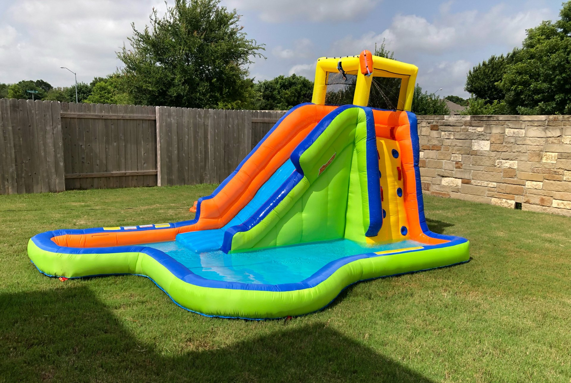 A large inflatable water park with a slide and a pool in a backyard.