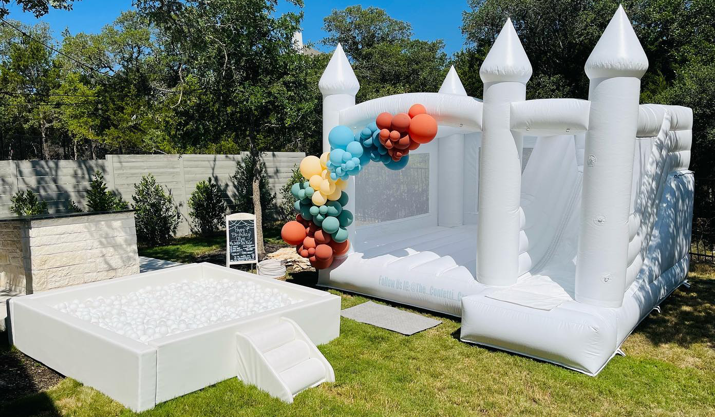 A white bouncy castle is sitting on top of a lush green field.