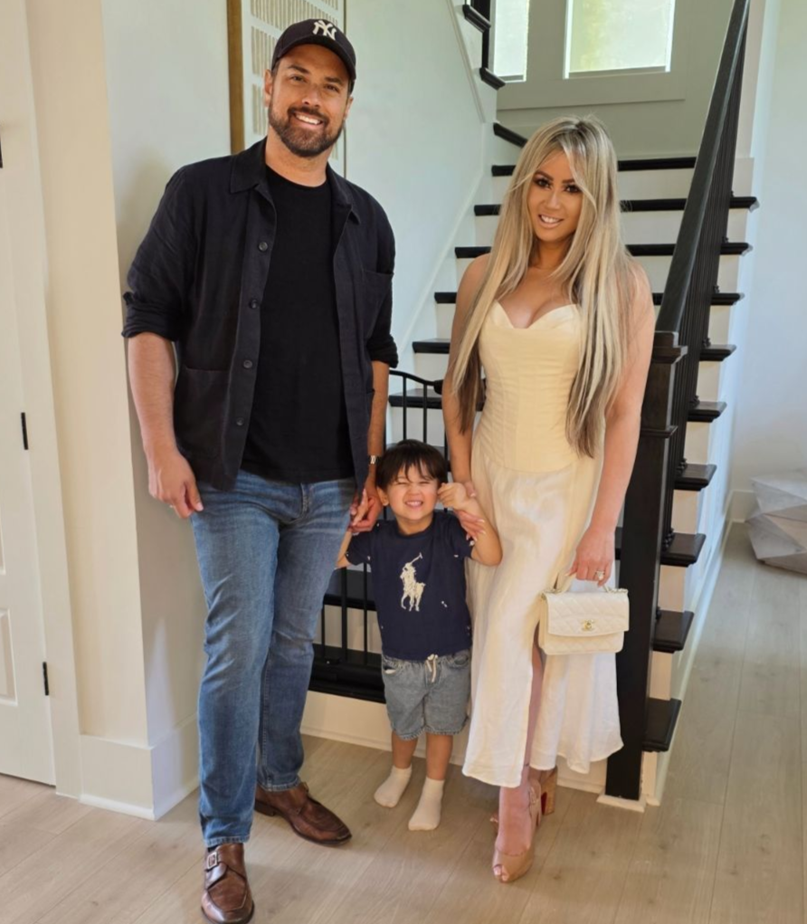 Del and his family stands inside by a staircase, smiling.