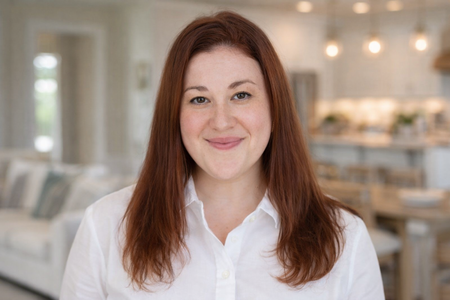 Jessica Cunningham with Aging in Place North Carolina - 
A person with shoulder-length reddish-brown hair, wearing a white collared shirt, smiles warmly in a bright home interior.