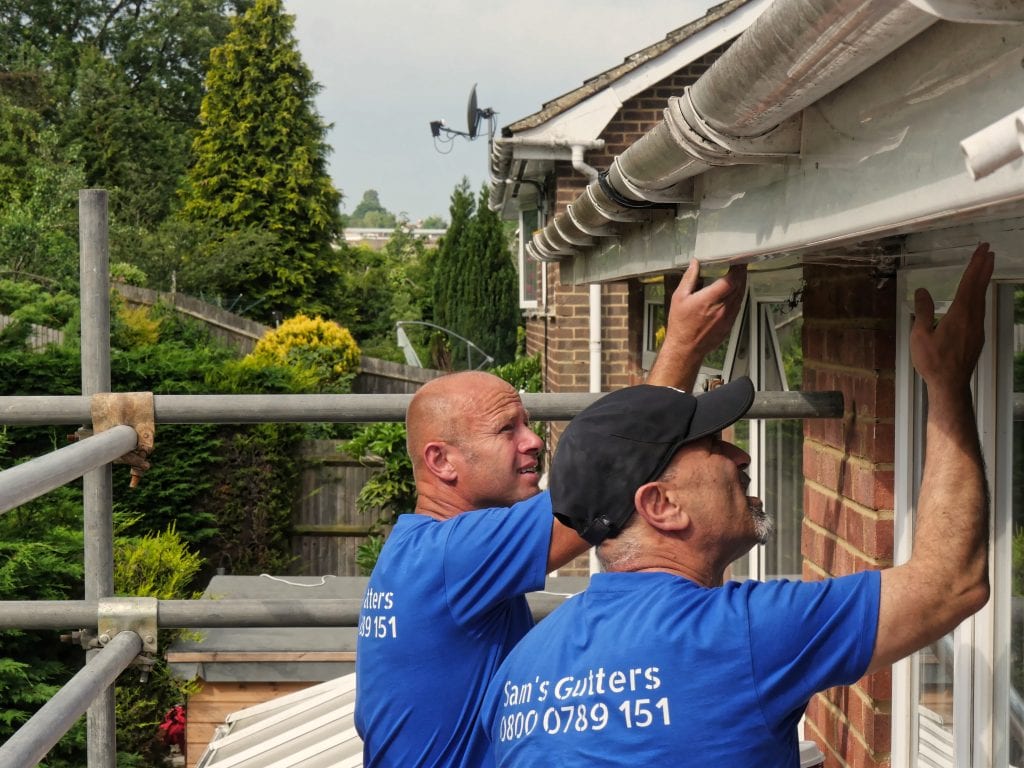 Roofers checking damage to gutters