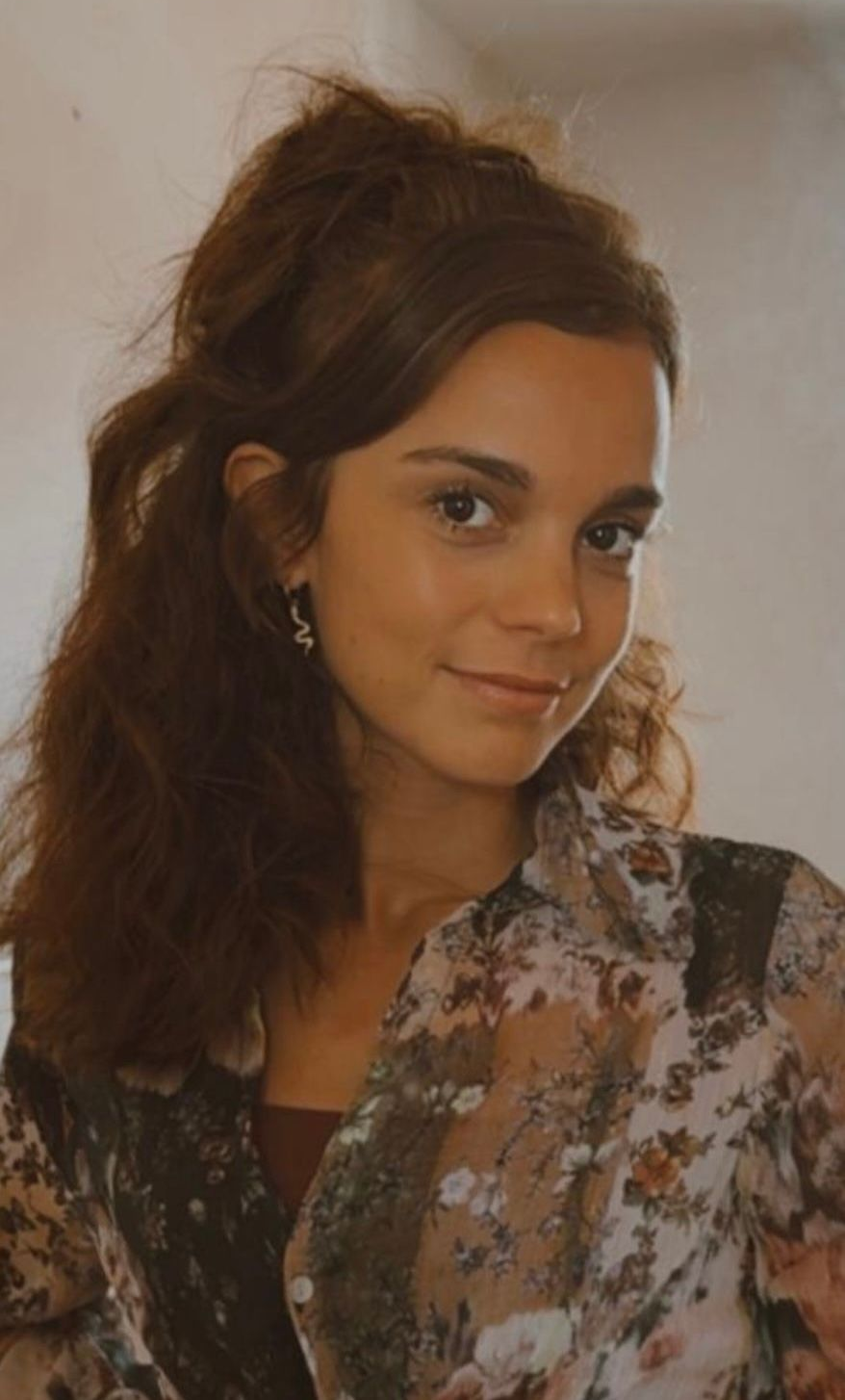 Een vrouw met lang bruin haar lacht buiten bij een kanaal, gekleed in een roze jasje.