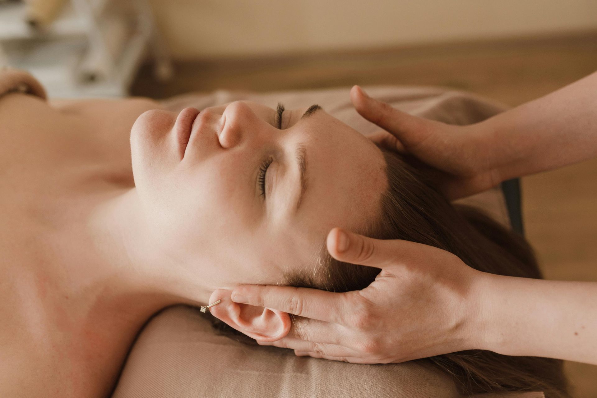 Handen masseren de blote rug van een persoon op een massagetafel.