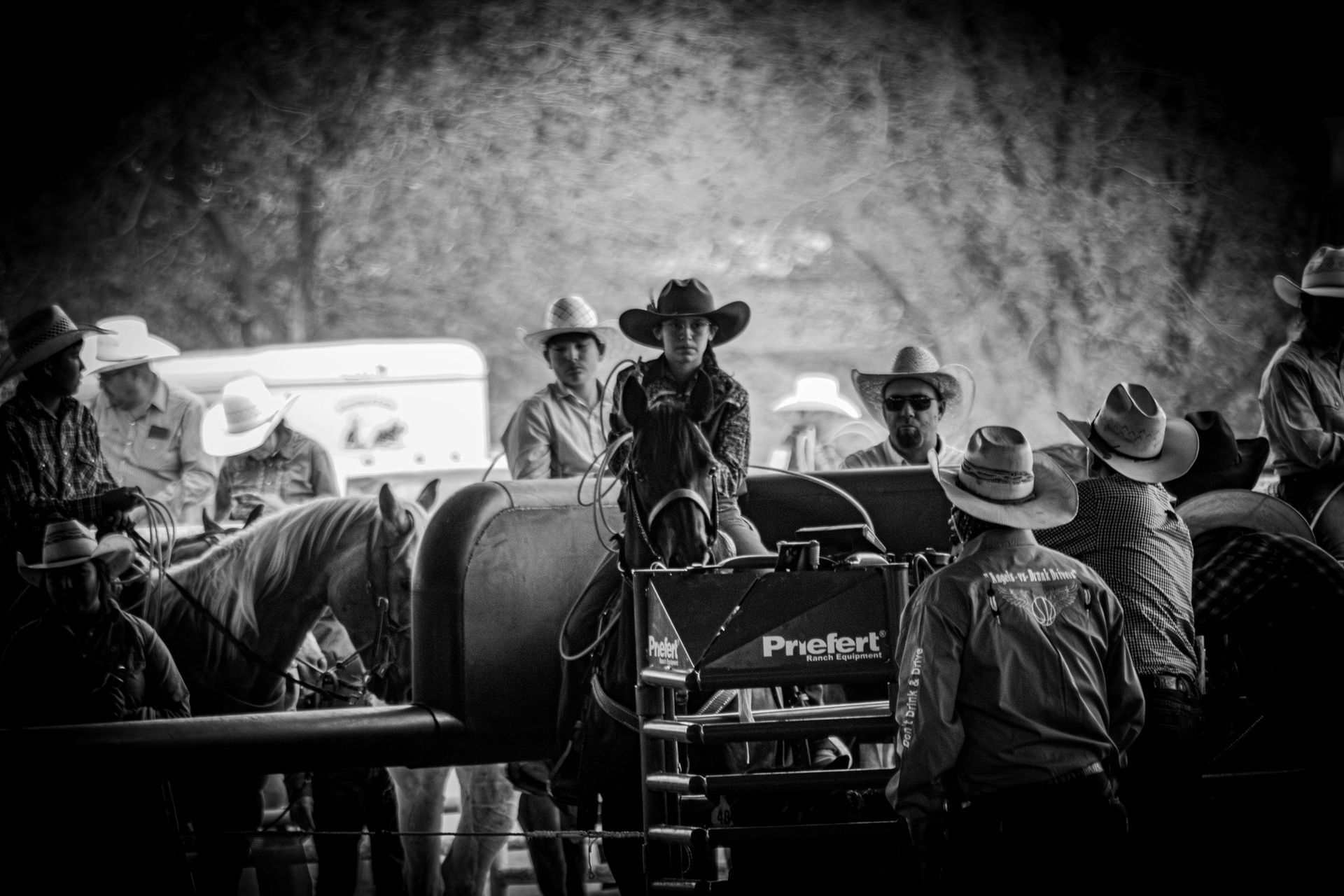 Cowboy on horseback at rodeo gate, surrounded by others, blurred background.
