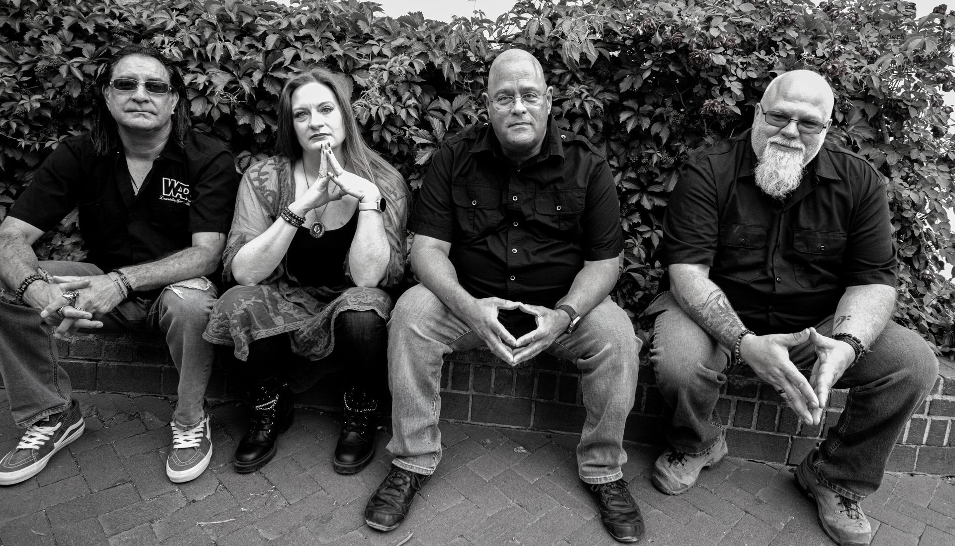 Four people sitting outdoors, posing for a photo. Black and white.