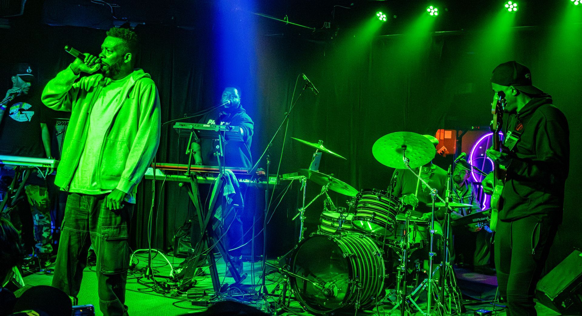Band performing on stage with green and blue lighting.