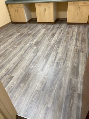 Room with gray wood-look flooring and light wood cabinets under a countertop.
