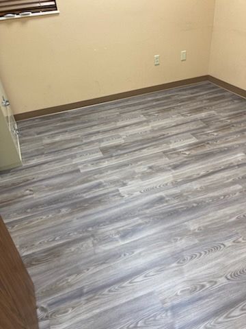 Gray wood-look flooring in a room with beige walls and a window.