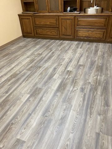 Wooden cabinets above gray wood-look flooring. Light-colored walls.