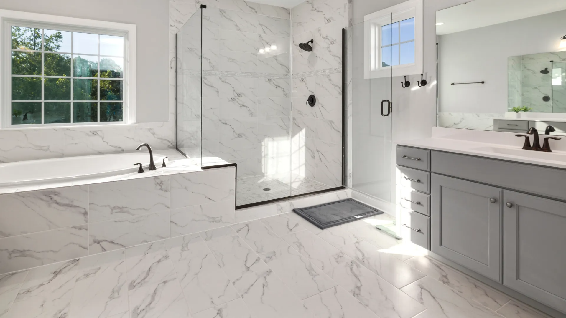 Bright, white marble bathroom with a bathtub, shower, and vanity. Black fixtures.