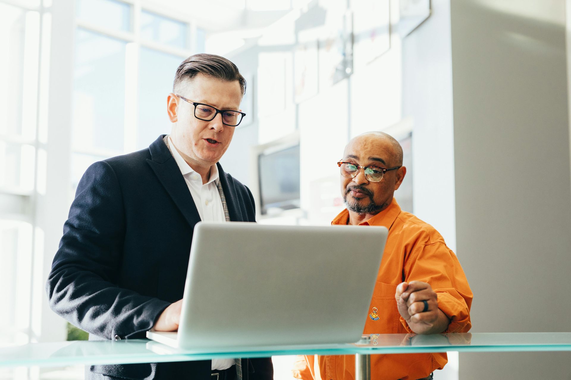 Tall caucasian man with latino man both looking at a laptop