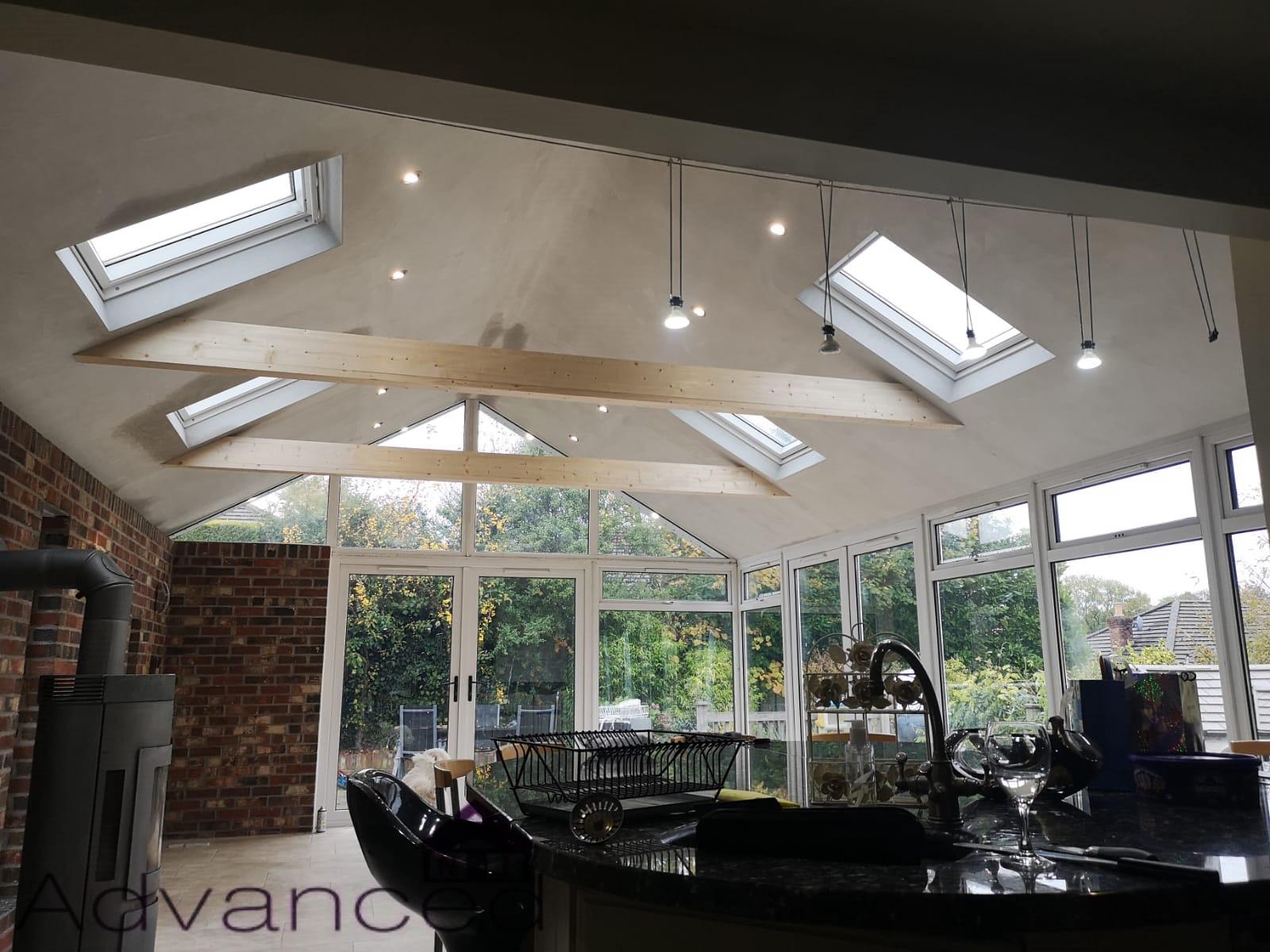 A kitchen with a lot of windows and skylights on the ceiling.