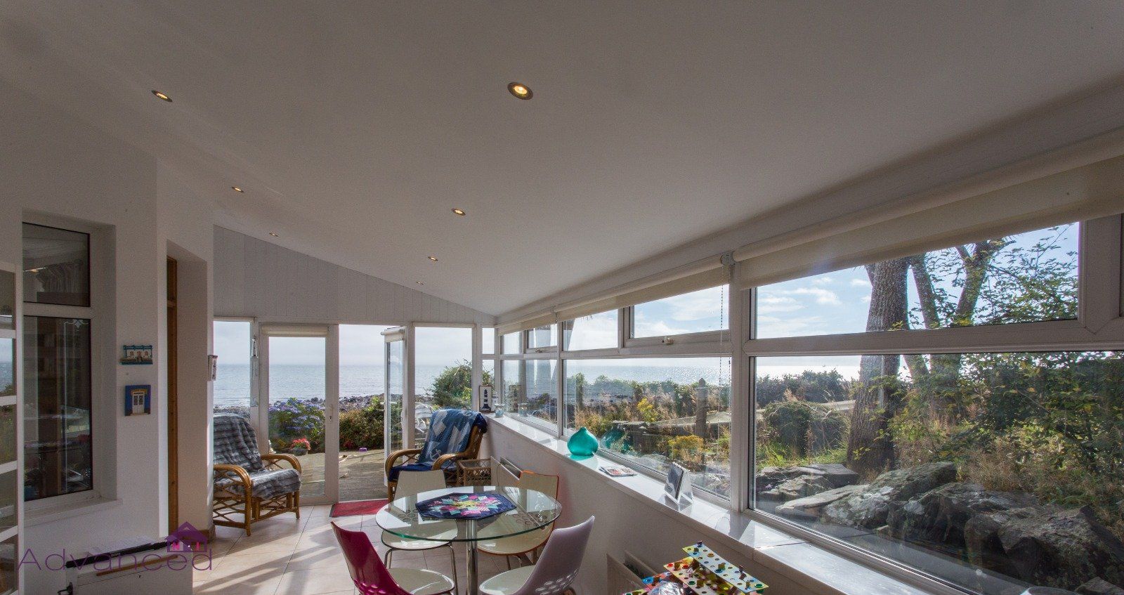 A living room with a lot of windows and a view of the ocean.
