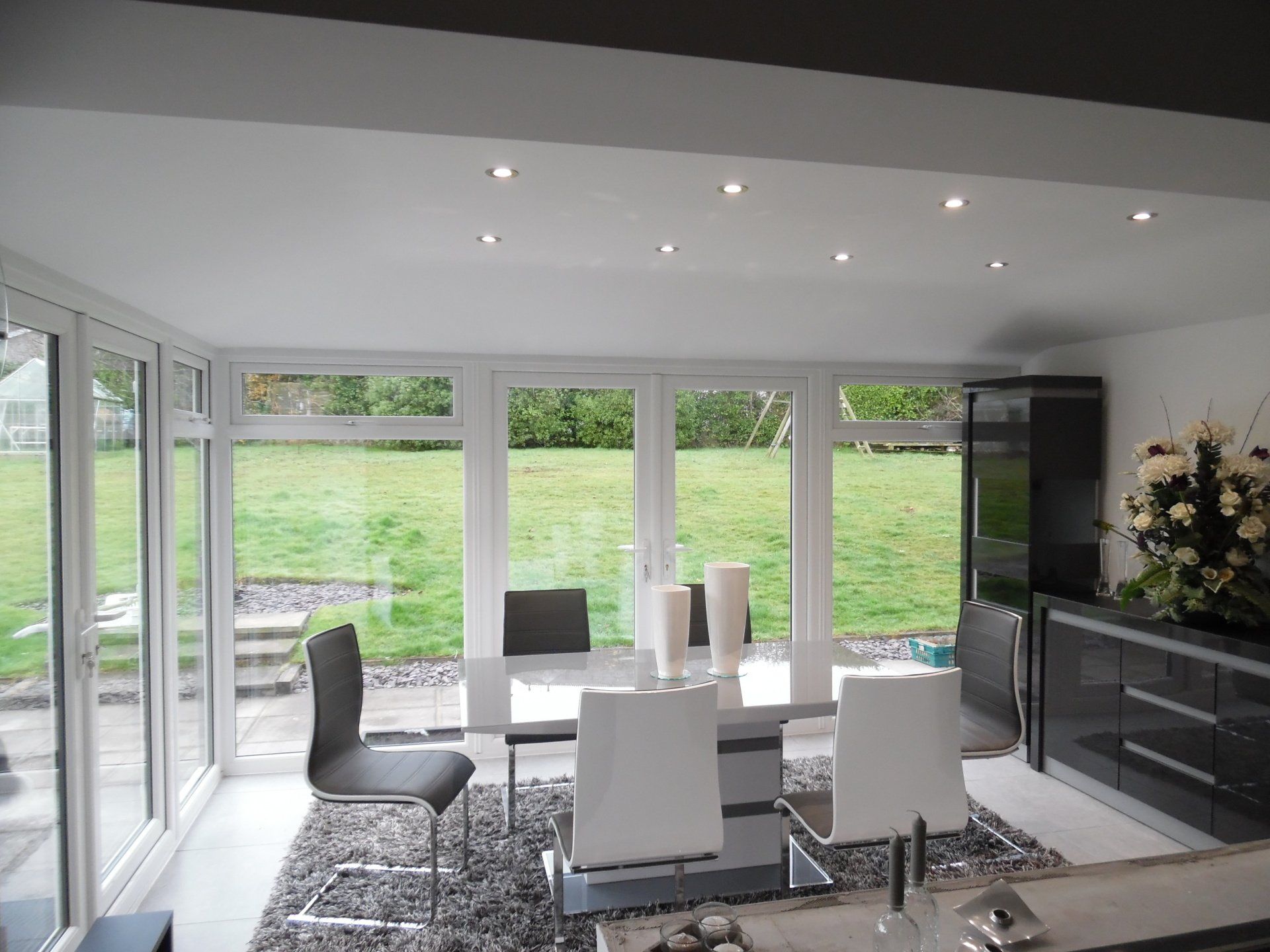 A dining room with a table and chairs and lots of windows